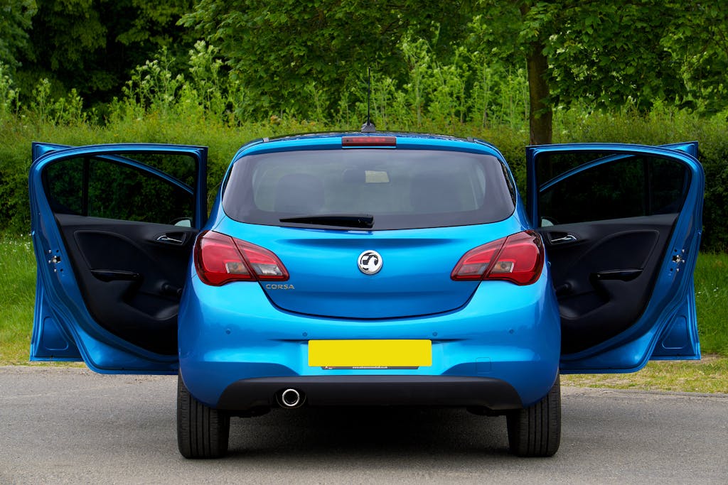 Rear view of a blue Vauxhall Corsa with open doors on a street.